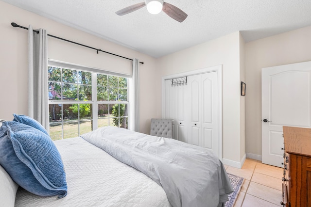 tiled bedroom with a closet, a textured ceiling, and ceiling fan