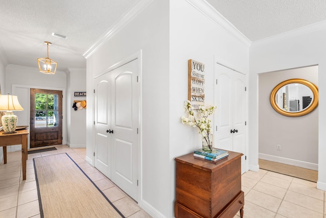 tiled entryway featuring a textured ceiling, a notable chandelier, and crown molding