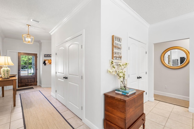 entryway with a textured ceiling, light tile patterned floors, ornamental molding, and baseboards