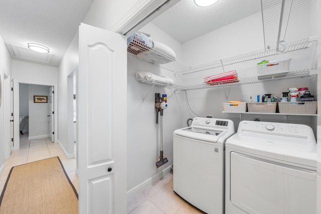 clothes washing area featuring separate washer and dryer, light tile patterned floors, attic access, a textured ceiling, and baseboards