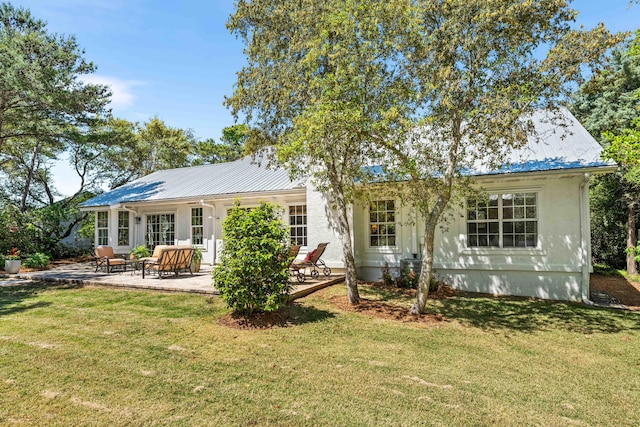 rear view of house featuring a yard, metal roof, and a patio