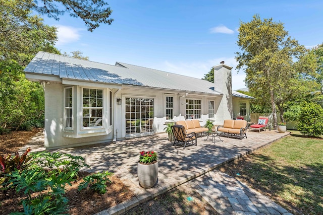 back of house with an outdoor hangout area, metal roof, a patio area, and stucco siding