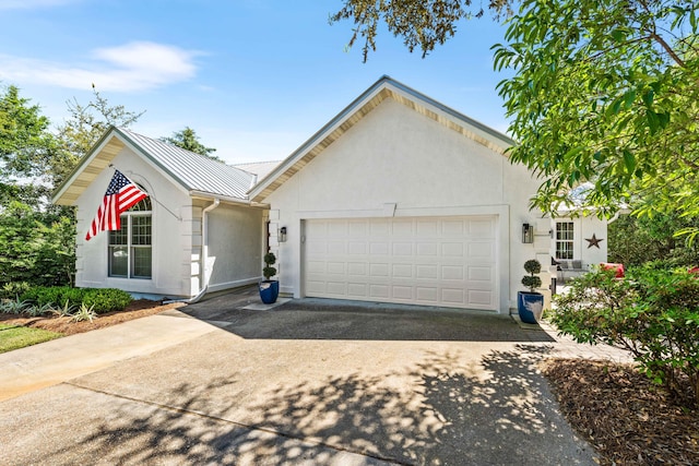 ranch-style house featuring driveway, stucco siding, a garage, metal roof, and a standing seam roof