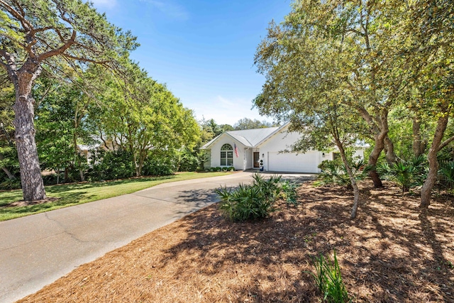 ranch-style home featuring driveway, an attached garage, and a front yard