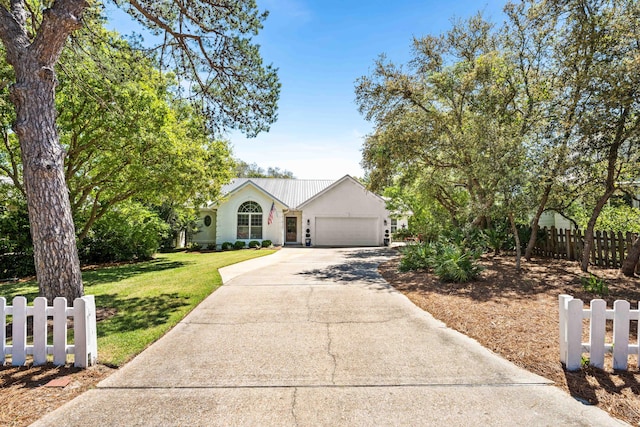 view of front of home with driveway, a garage, stucco siding, and metal roof