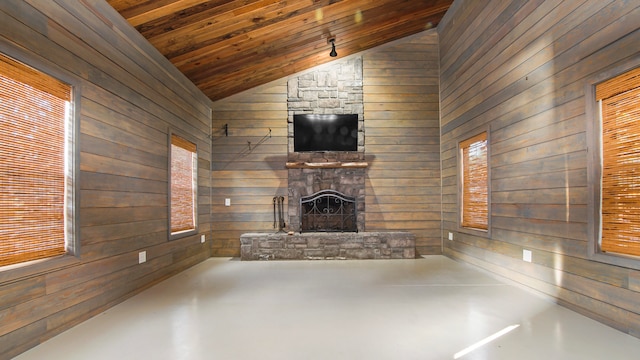 unfurnished living room with wood walls, wooden ceiling, concrete flooring, a stone fireplace, and lofted ceiling