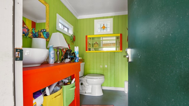 bathroom featuring toilet, concrete flooring, and crown molding