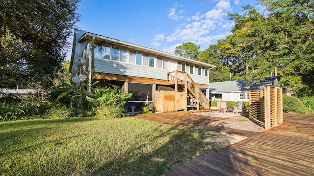 rear view of property with a patio, a sunroom, a lawn, and a deck