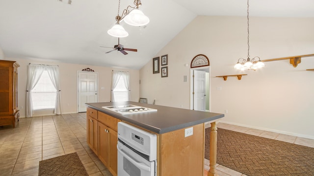 kitchen featuring ceiling fan with notable chandelier, light tile patterned floors, white cooktop, an island with sink, and high vaulted ceiling