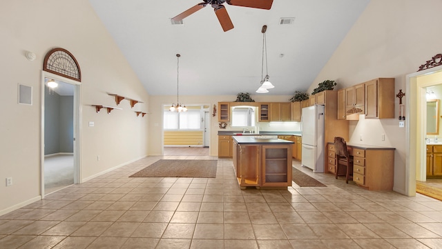 kitchen featuring ceiling fan with notable chandelier, high vaulted ceiling, hanging light fixtures, a kitchen island, and white fridge