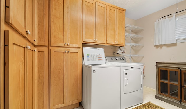 laundry room with washer and clothes dryer, cabinets, and a textured ceiling