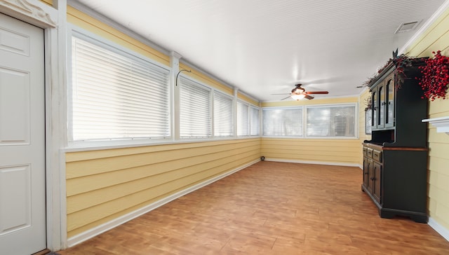 unfurnished sunroom with ceiling fan