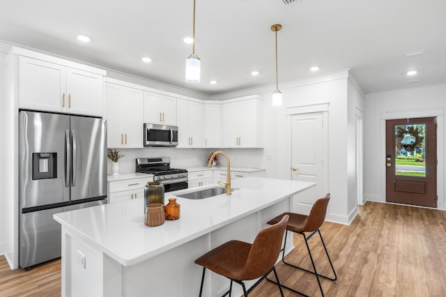 kitchen with sink, an island with sink, hanging light fixtures, and appliances with stainless steel finishes