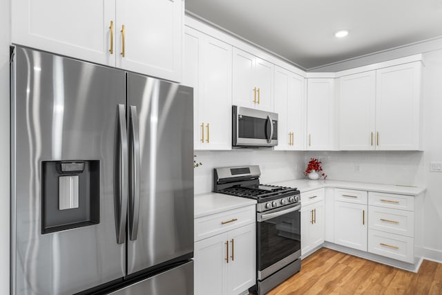 kitchen featuring tasteful backsplash, white cabinetry, stainless steel appliances, and light hardwood / wood-style floors