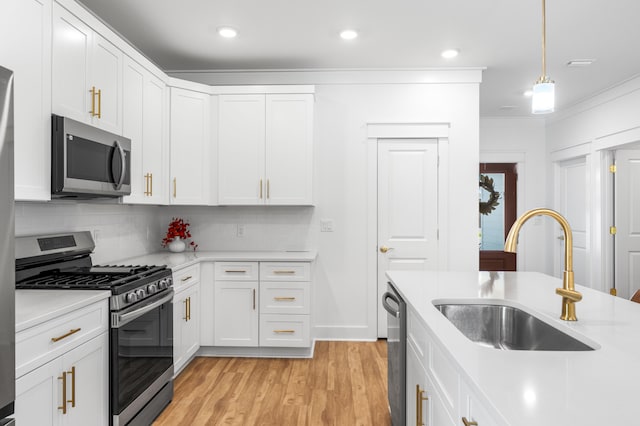 kitchen with decorative backsplash, stainless steel appliances, sink, light hardwood / wood-style flooring, and white cabinetry