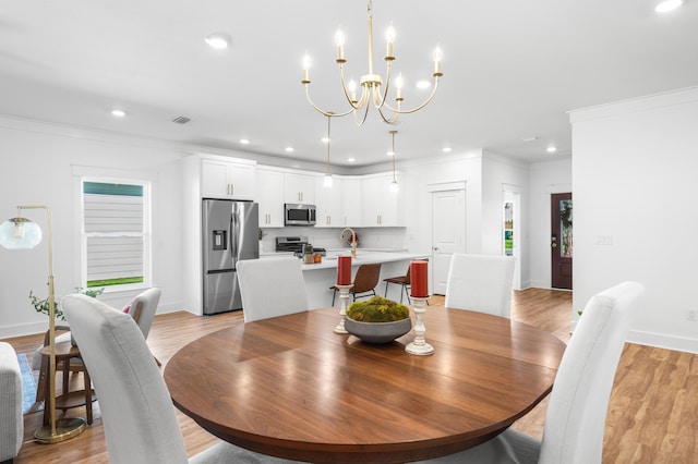 dining area featuring a chandelier, light hardwood / wood-style floors, ornamental molding, and sink