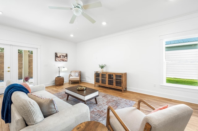 living room featuring french doors, light wood-type flooring, ceiling fan, and ornamental molding