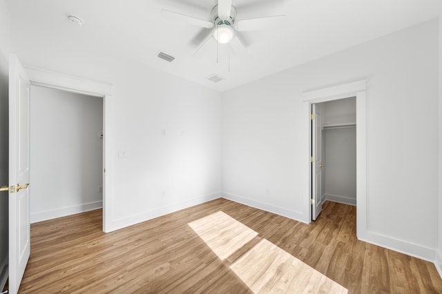 unfurnished bedroom with ceiling fan, light wood-type flooring, and a closet