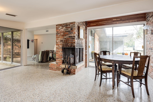 dining room with a healthy amount of sunlight, brick wall, and a brick fireplace