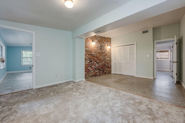 empty room with ceiling fan, light carpet, and brick wall