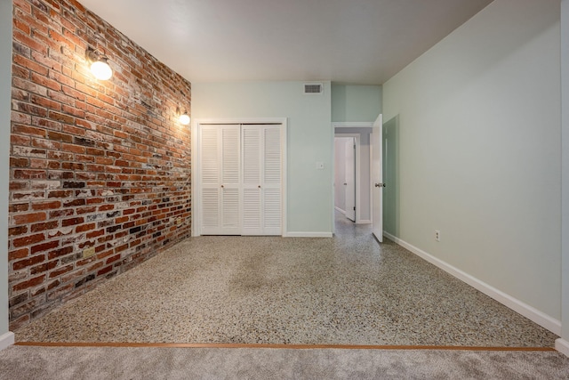 unfurnished bedroom featuring brick wall and a closet