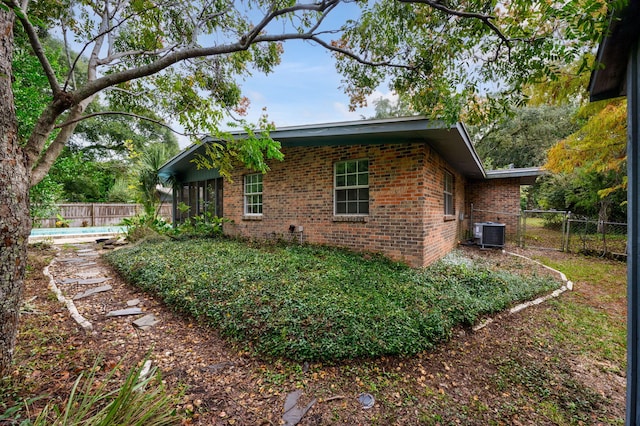 view of side of property featuring a fenced in pool and central air condition unit