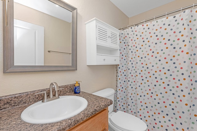 bathroom with curtained shower, vanity, and toilet