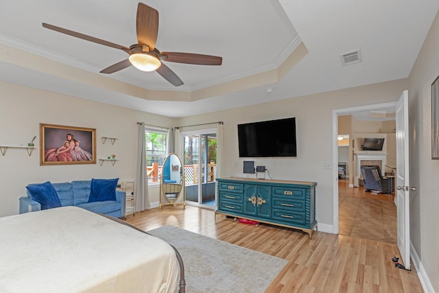 bedroom featuring ornamental molding, light hardwood / wood-style floors, ceiling fan, and a tray ceiling