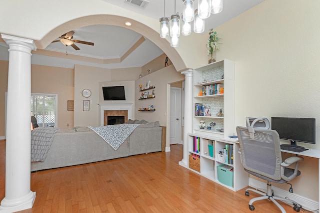 office space with light hardwood / wood-style floors, ceiling fan, a tray ceiling, crown molding, and a tile fireplace