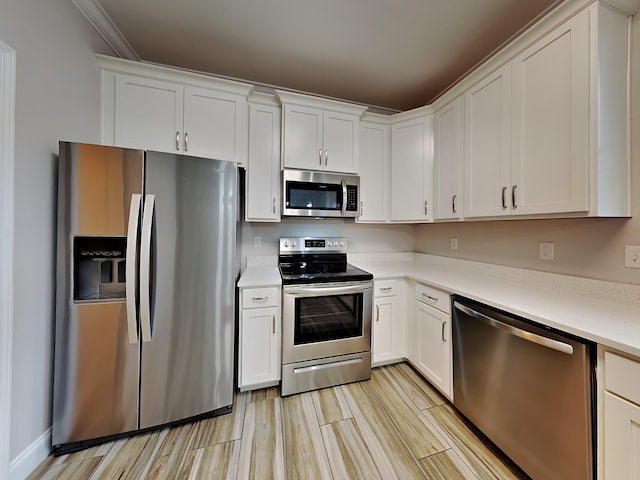 kitchen with ornamental molding, stainless steel appliances, and white cabinets