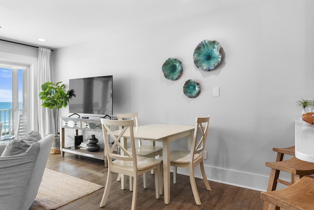 dining space with dark hardwood / wood-style flooring and a water view