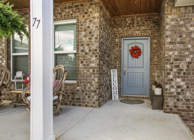 doorway to property featuring brick siding and a porch