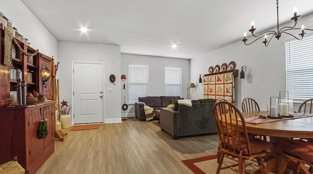 dining room with light wood-type flooring, visible vents, a chandelier, and baseboards