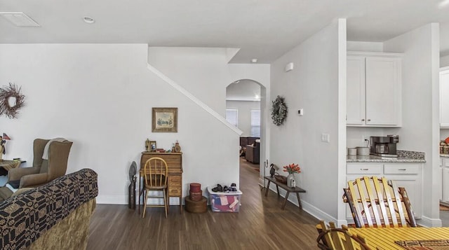 interior space with arched walkways, dark wood-type flooring, visible vents, and baseboards