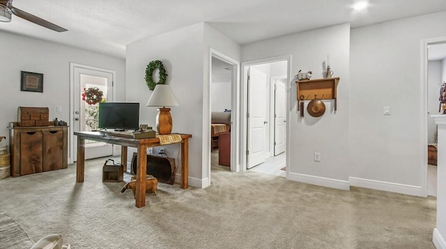 office featuring light carpet, ceiling fan, and baseboards