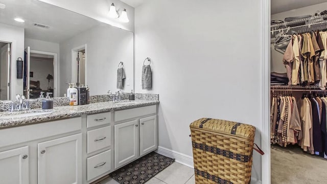 full bath with a sink, double vanity, a walk in closet, and visible vents