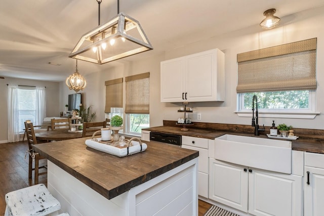 kitchen with dark hardwood / wood-style flooring, white cabinets, butcher block countertops, a kitchen island, and pendant lighting