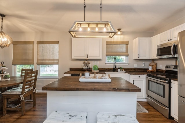 kitchen with wooden counters, stainless steel appliances, dark hardwood / wood-style floors, a kitchen island, and pendant lighting