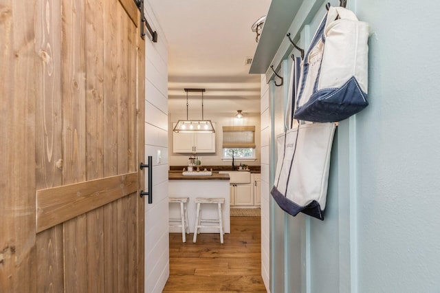 corridor with sink, a barn door, and light hardwood / wood-style floors