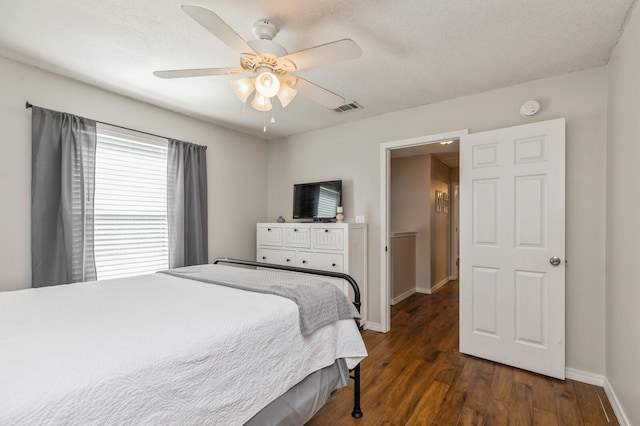 bedroom with a textured ceiling, ceiling fan, and dark hardwood / wood-style floors