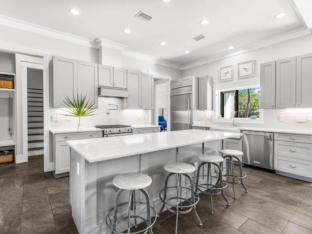 kitchen featuring light stone counters, backsplash, a kitchen breakfast bar, high end appliances, and a center island