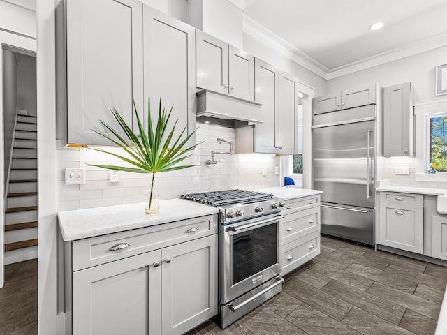 kitchen with ornamental molding, backsplash, light stone counters, and high quality appliances