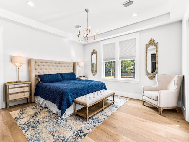 bedroom featuring an inviting chandelier and light hardwood / wood-style flooring