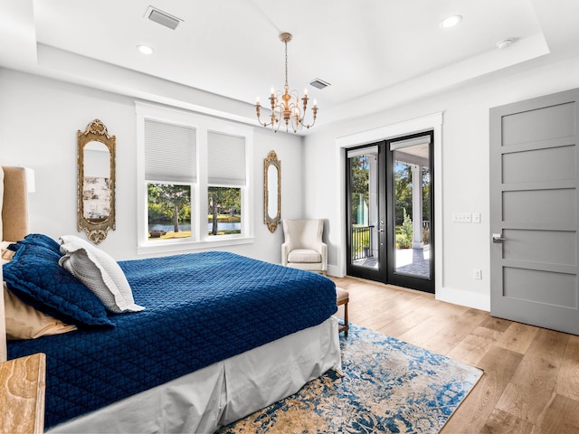 bedroom featuring light hardwood / wood-style flooring, an inviting chandelier, and access to exterior