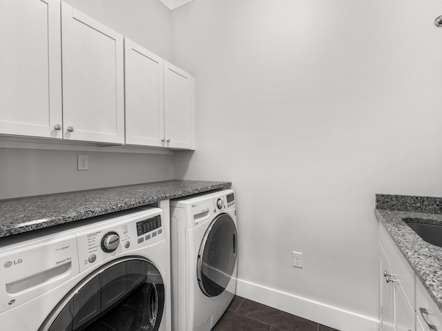 laundry area featuring cabinets, dark tile patterned floors, and washer and clothes dryer