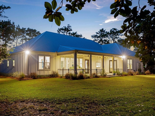 back house at dusk with a lawn