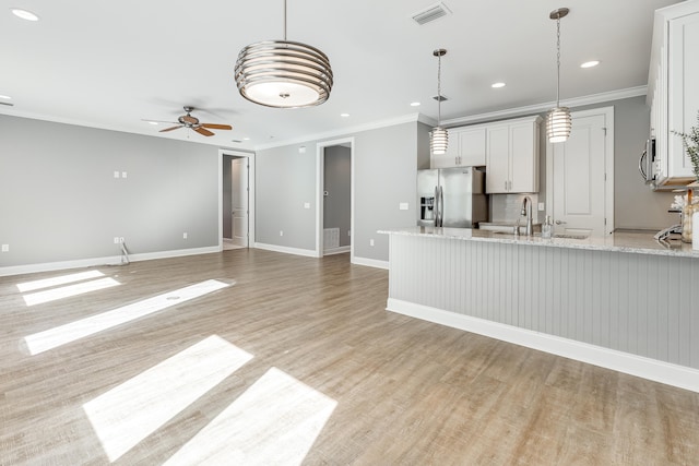 kitchen with white cabinets, decorative light fixtures, light stone counters, and stainless steel appliances