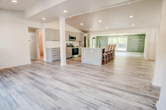 unfurnished living room with sink, lofted ceiling with beams, light hardwood / wood-style flooring, and wood ceiling