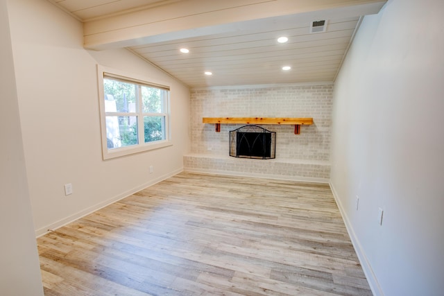 unfurnished living room featuring lofted ceiling with beams, light wood-type flooring, a fireplace, wood ceiling, and ornamental molding