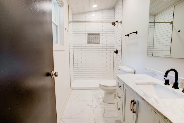 bathroom with toilet, a tile shower, vanity, and vaulted ceiling